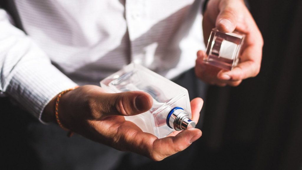 Muškarac drži bočicu parfema u ruci